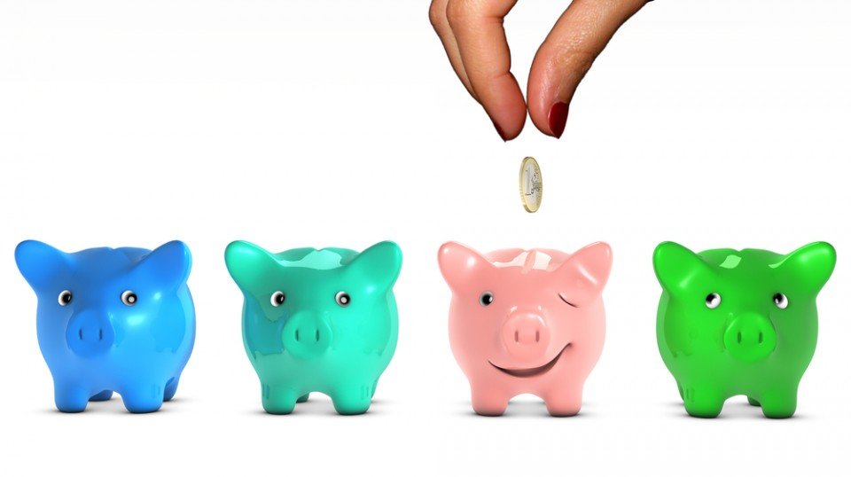 Four colored piggy banks with the pink one winking