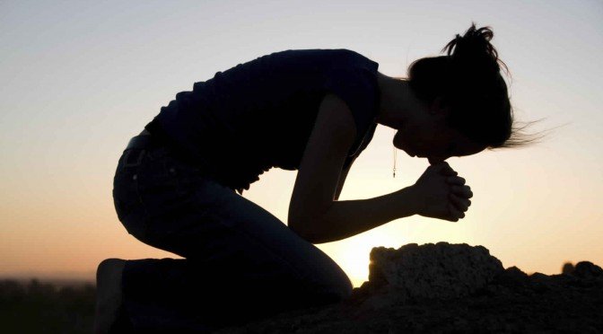 A women bent in prayer to God