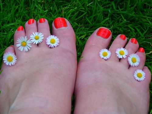 Brightly painted toe nails with flowers between toes