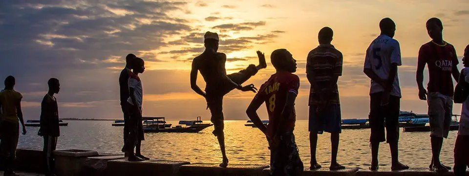 Boys play about on the wall at the waterfront at Forodhani Garden, Zanzibar