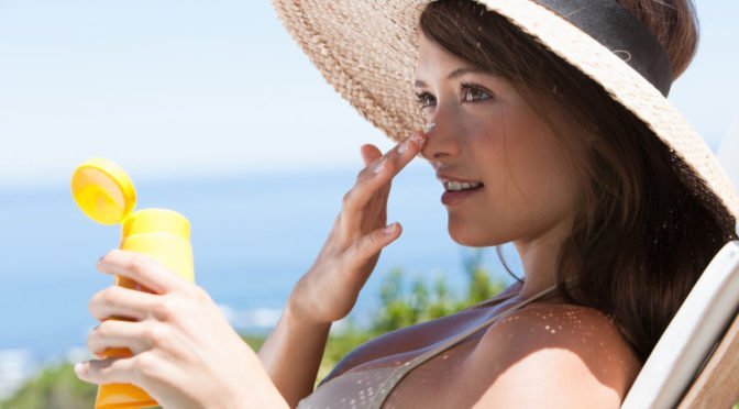 Woman applying sunscreen on face