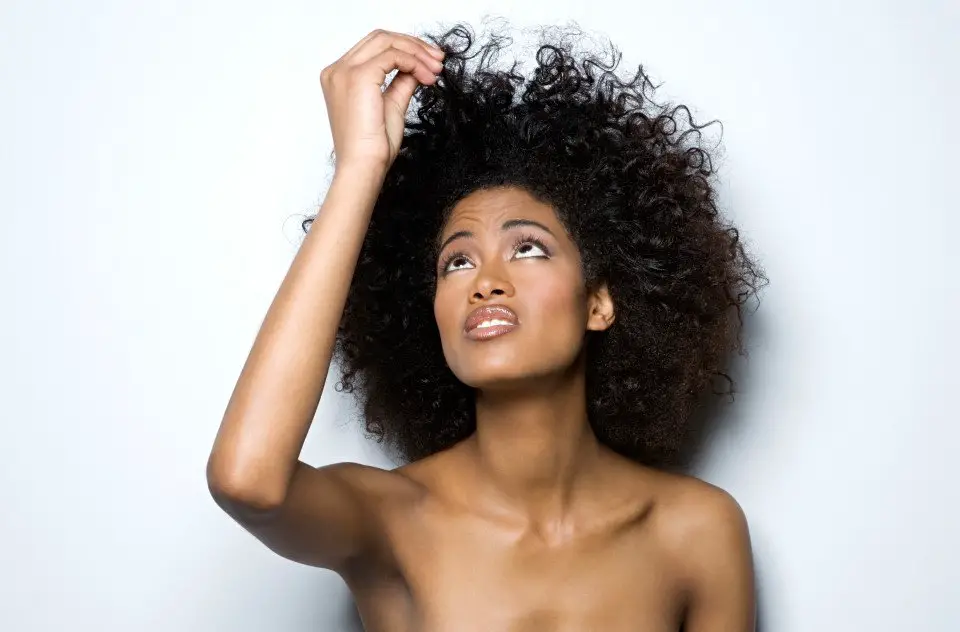 Black Woman looking at damaged natural hair