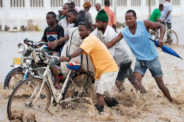 People pushing bikes through water in Dar es Salaam