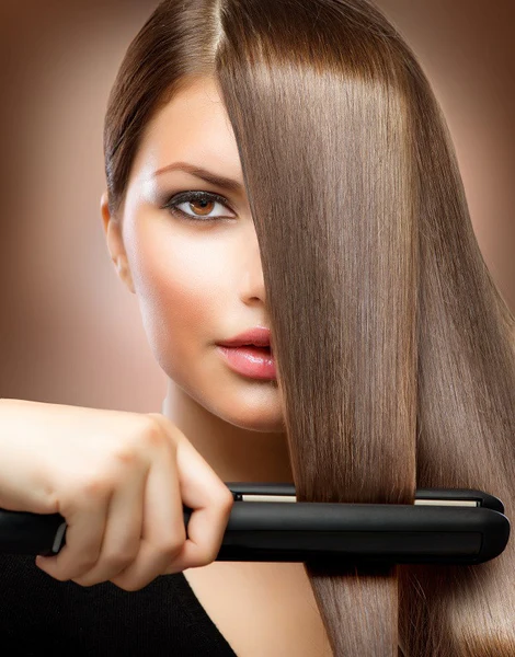 Woman straigtening hair with a hair iron