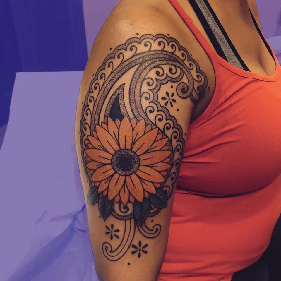 Coloured Tattoos on Dark Skin females: a beautiful orange flower and geometric design on upper arm
